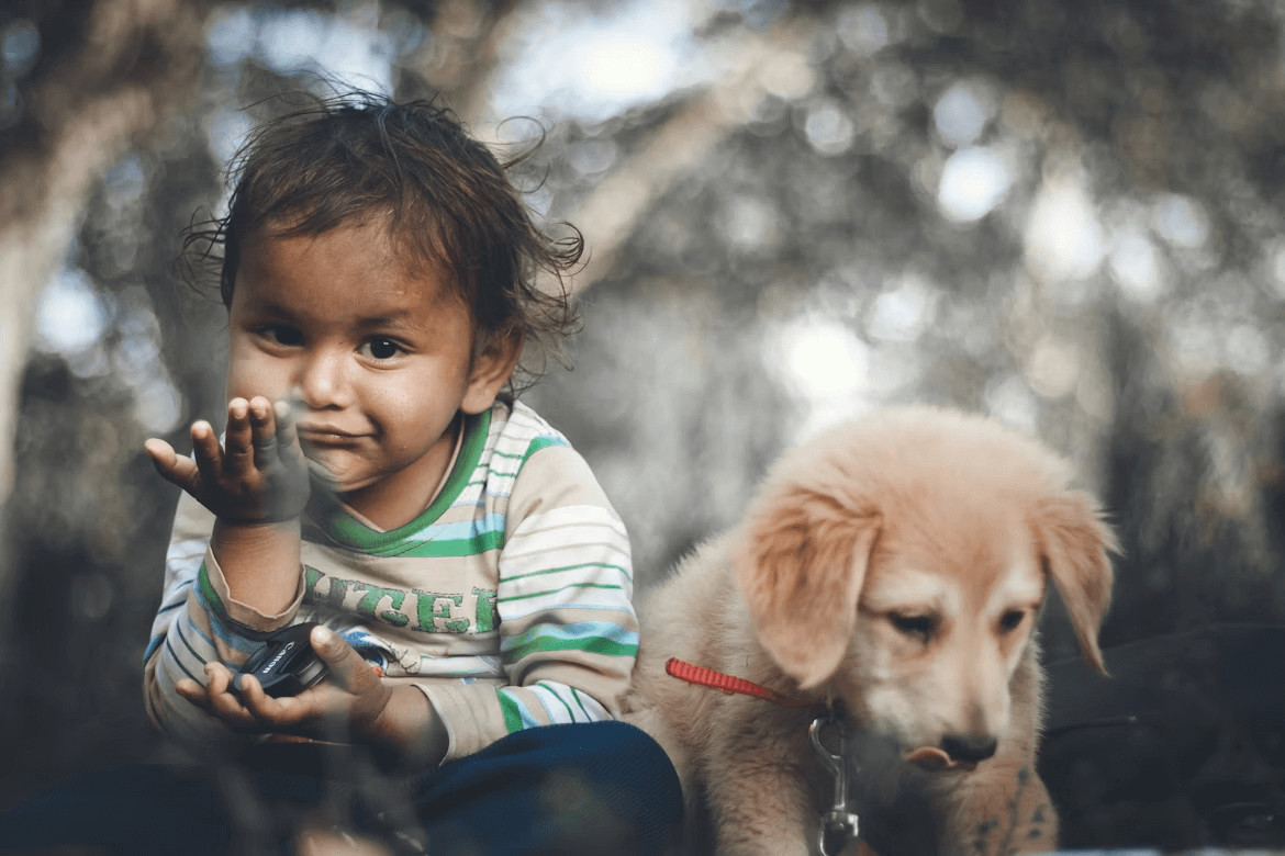 Baby sitting beside a dog, showcasing child and pet interaction