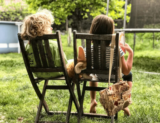 Two girls in wooden chairs enjoying a grassy