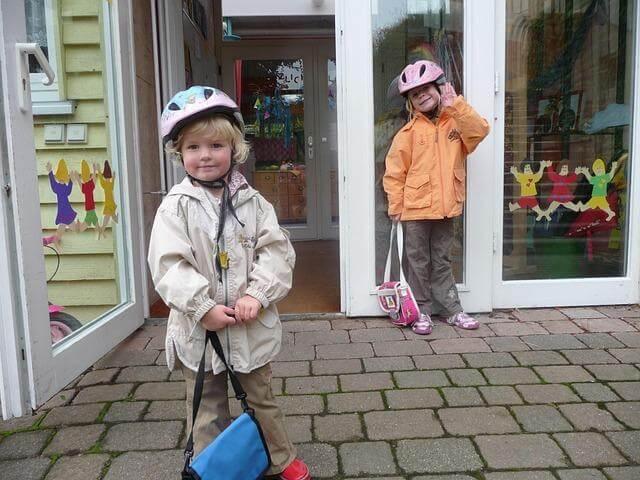 Two children with helmets in front of a store