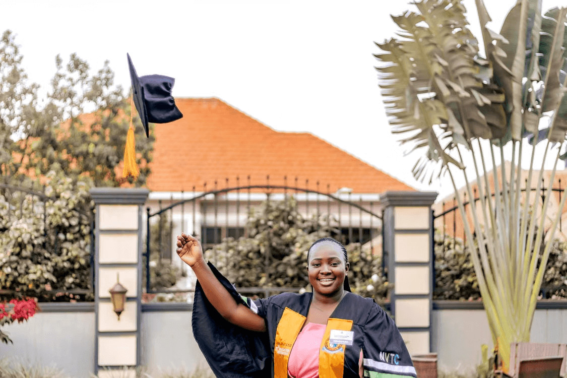 A happy woman in a graduation cap and gown celebrates