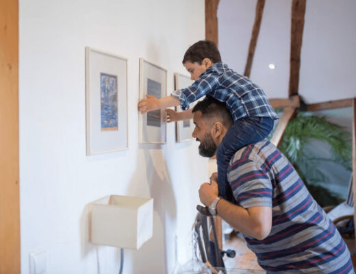 Father and son hanging pictures, demonstrating a family home