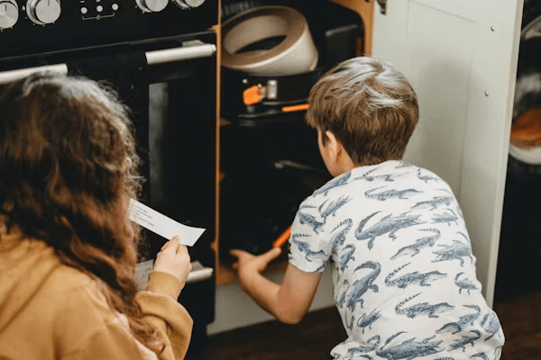 Kids looking into an oven, ready to bake