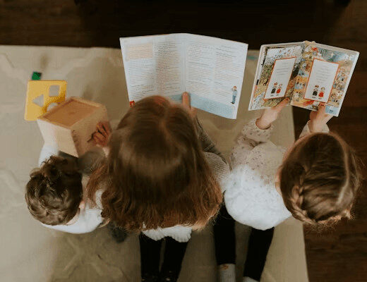 Two children read books at a table