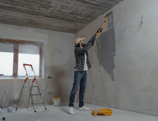 Man painting a room with a roller, preparing for
