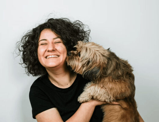 Woman smiling and holding a dog, embodying