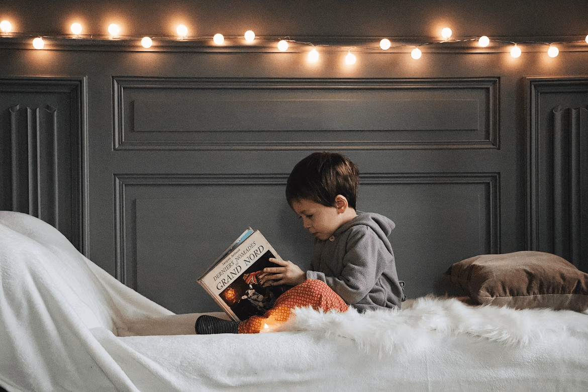 Young boy reading a book in bed