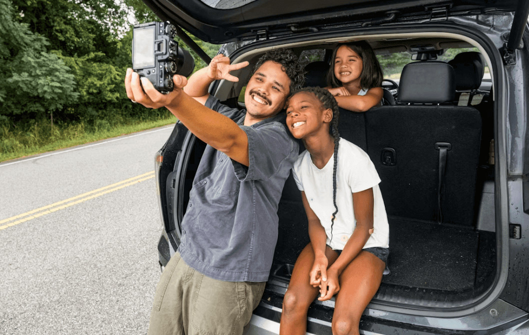 Man photographing a family in the back of a car