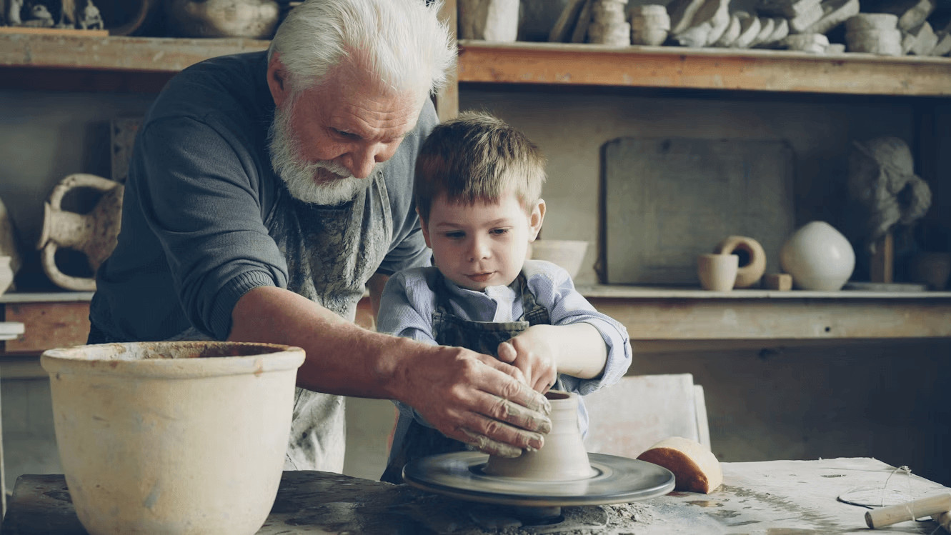 Older man and young boy crafting pottery together on a