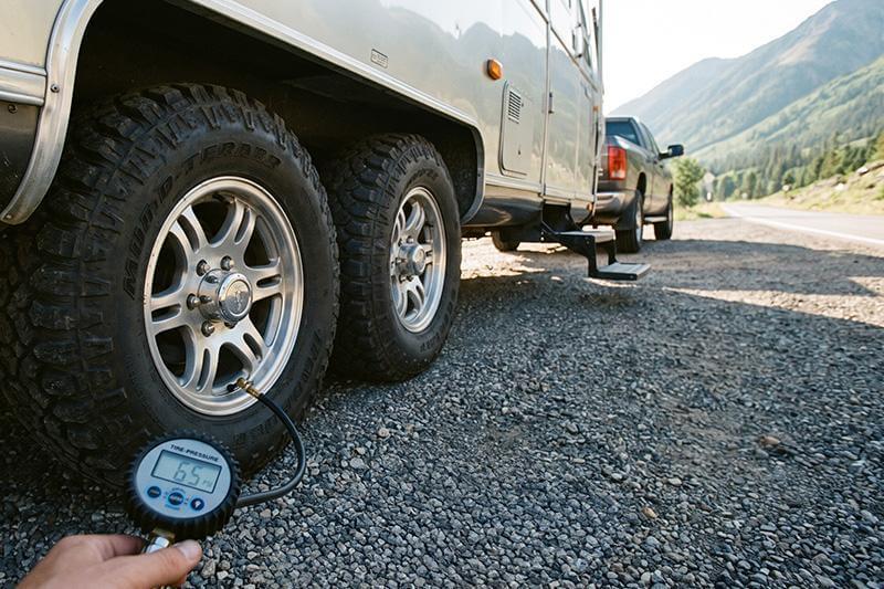Person checking truck tire pressure before a road trip