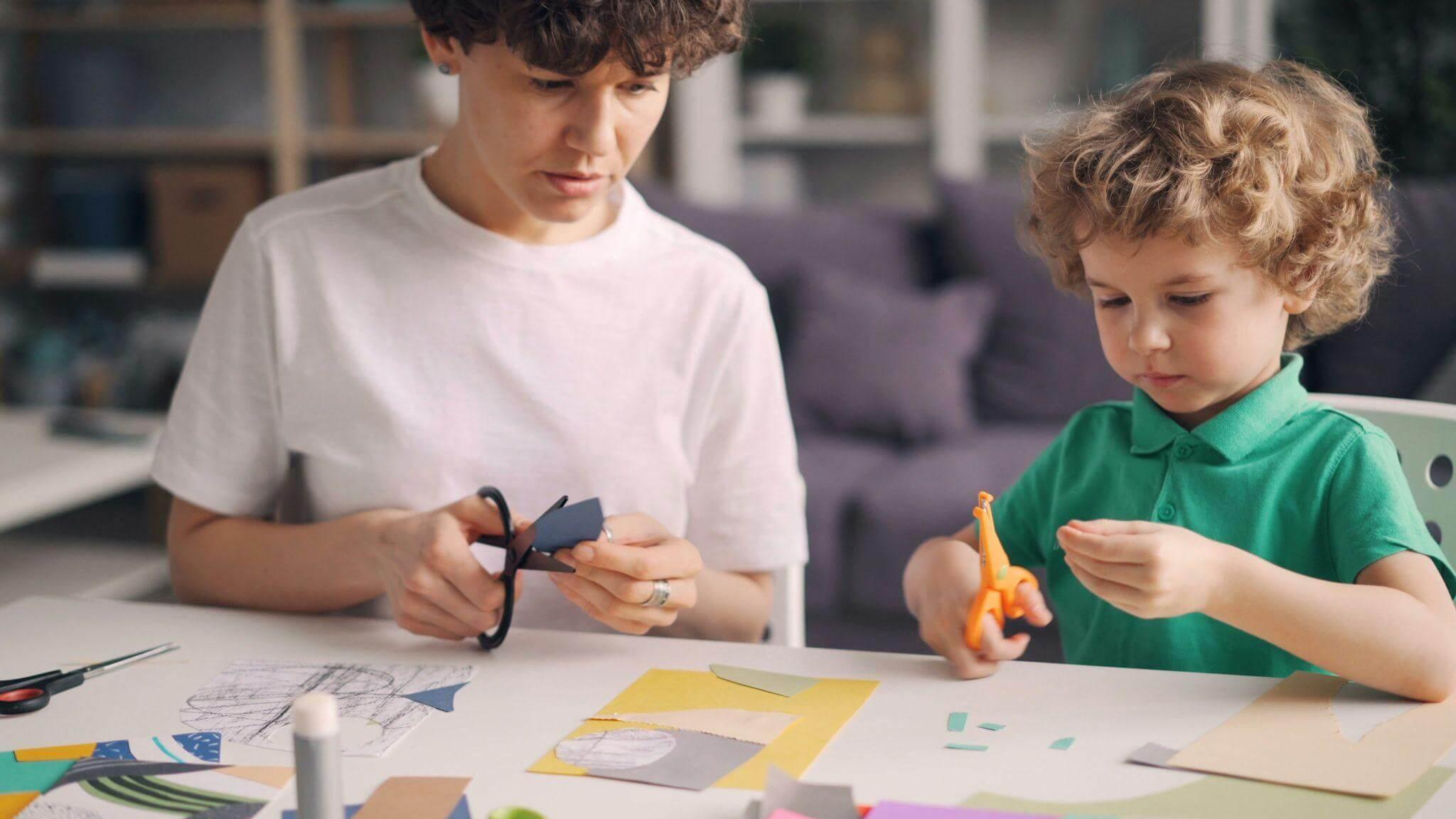 Two boys crafting with scissors at a table