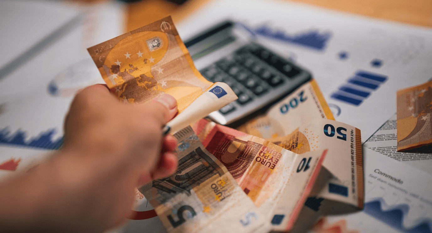 Person holding money in front of a calculator,